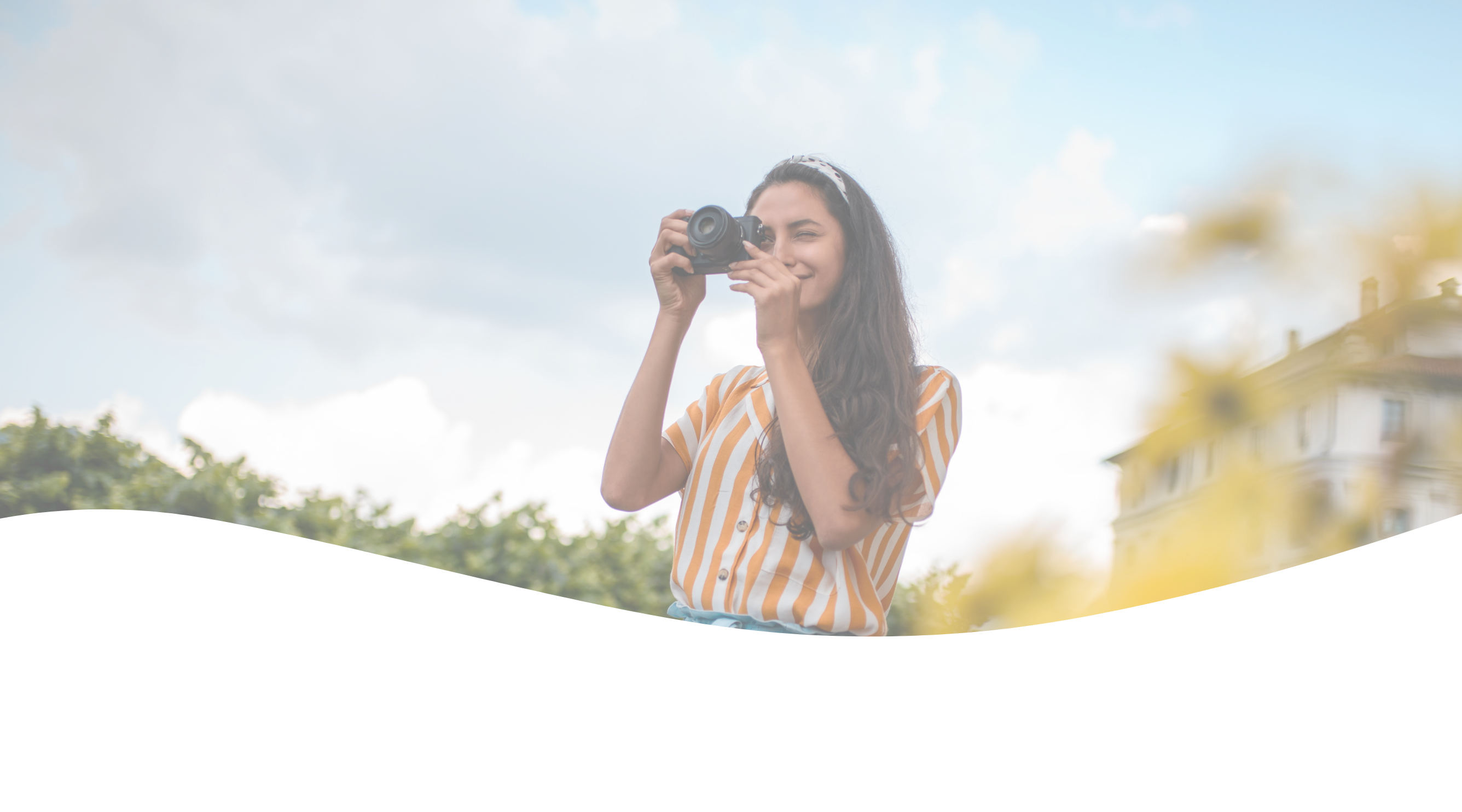 Smiling woman using a camera, perfecting her skills with photography cheat cards, against a light green background.