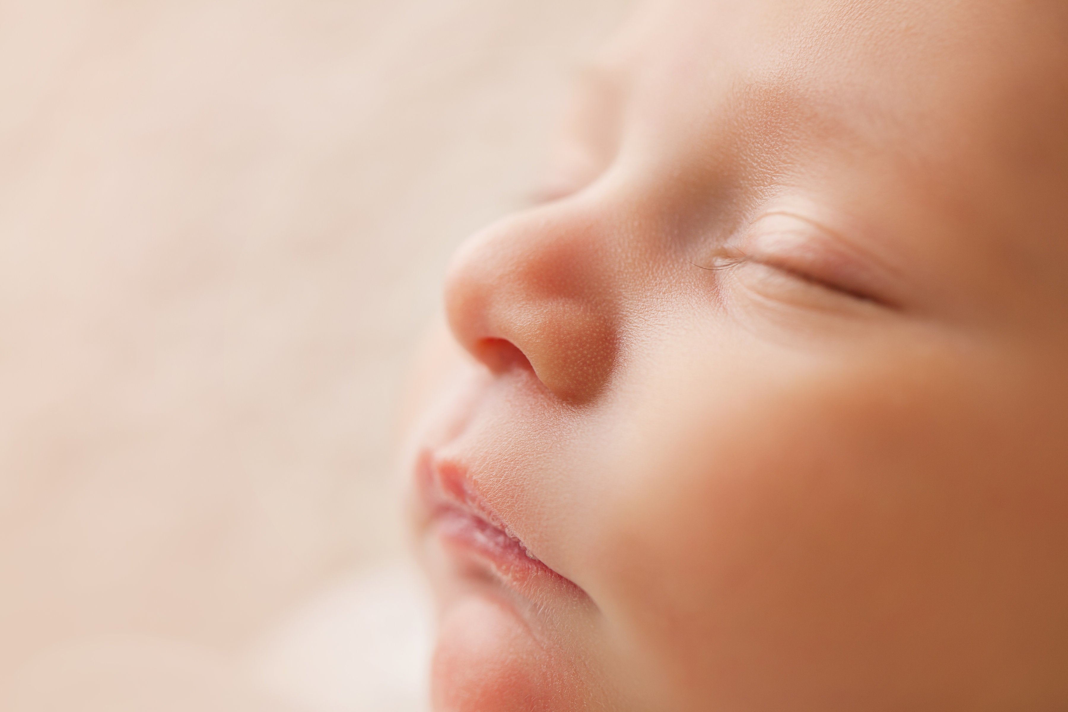 Close-up of a sleeping newborn baby with soft lighting and a peaceful expression.