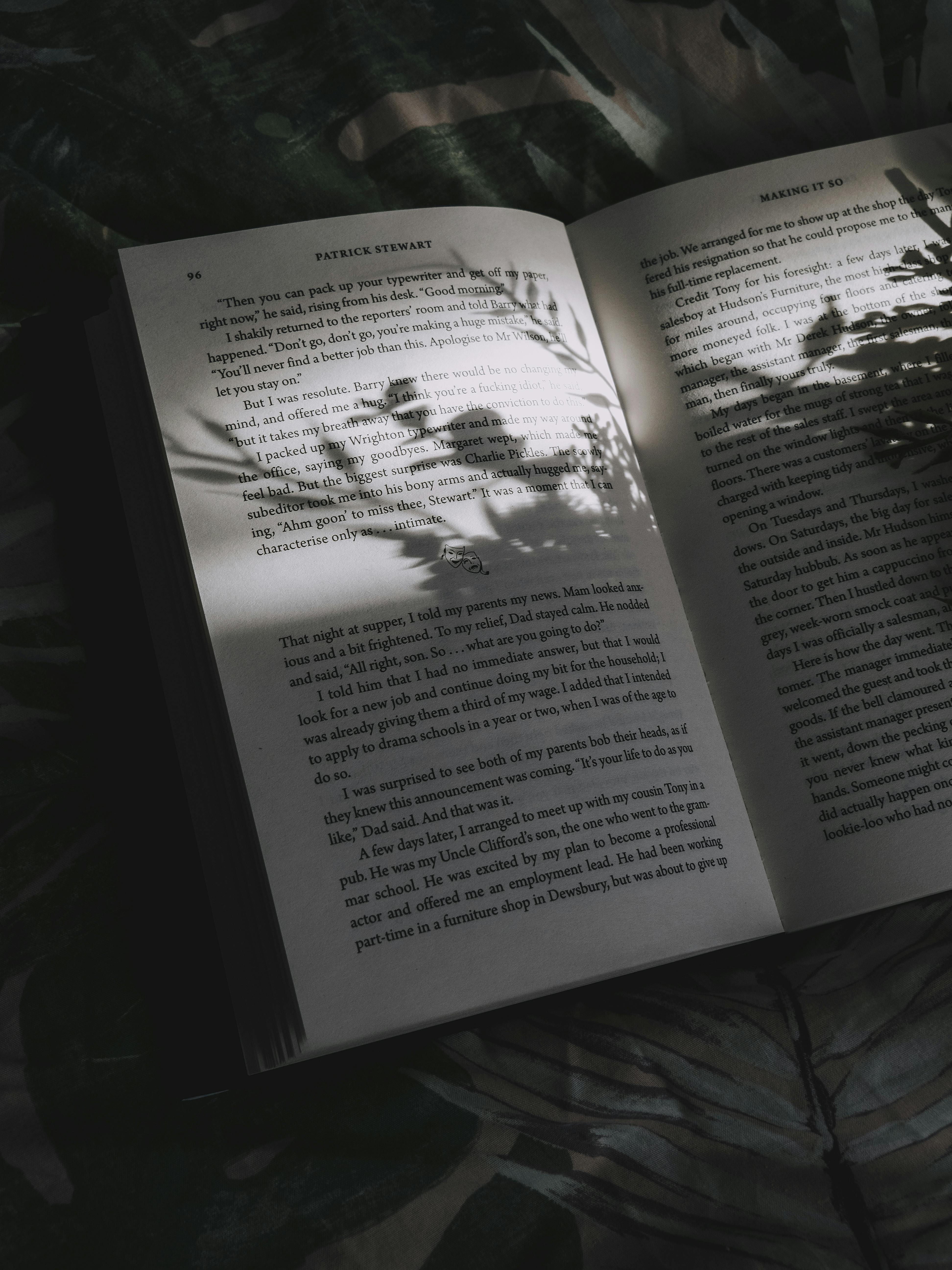 Open book with soft shadows of leaves cast across the pages, creating a moody and tranquil atmosphere.