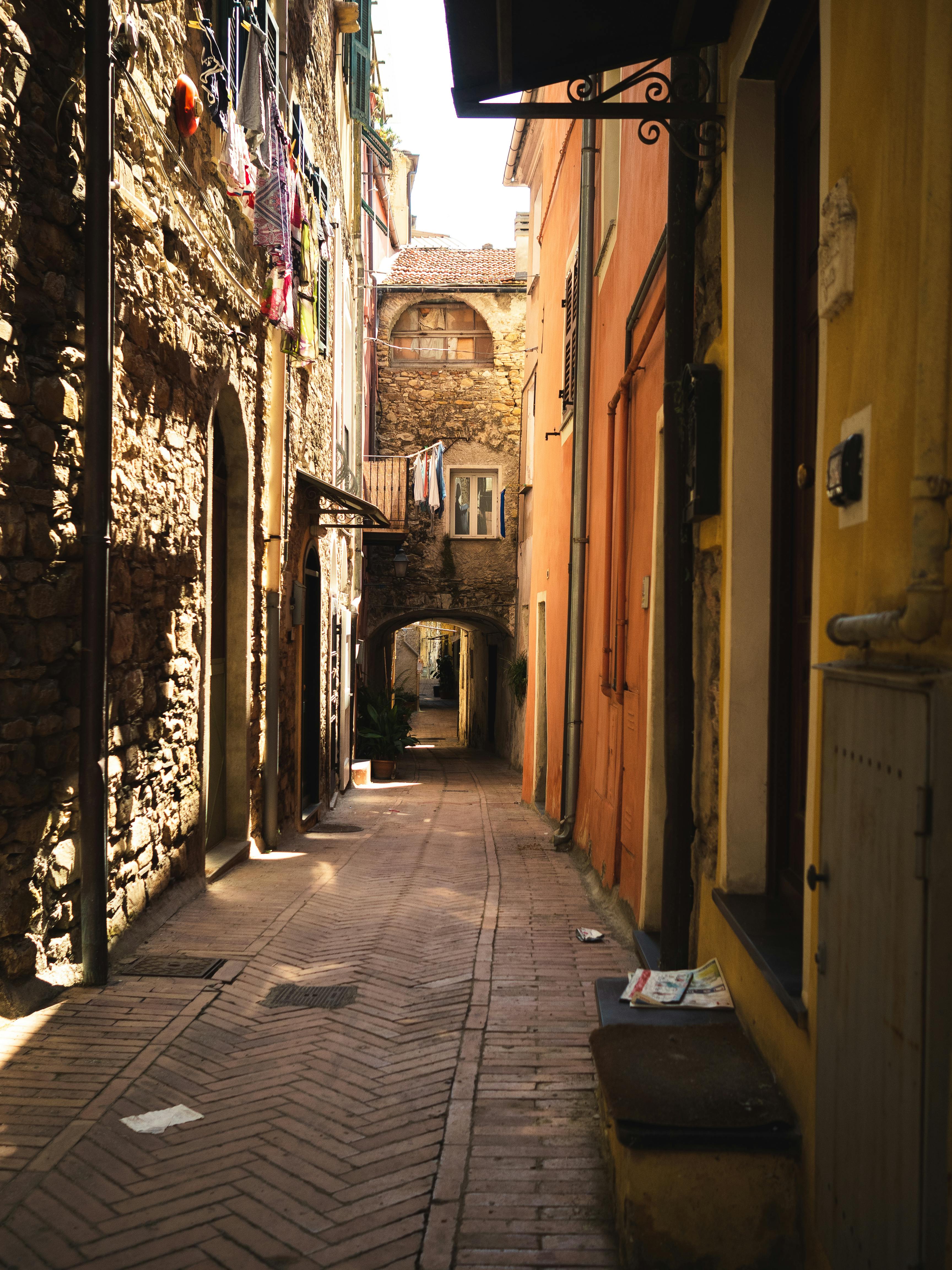 Narrow cobblestone alleyway between rustic buildings in a historic European town, illuminated by soft natural light.